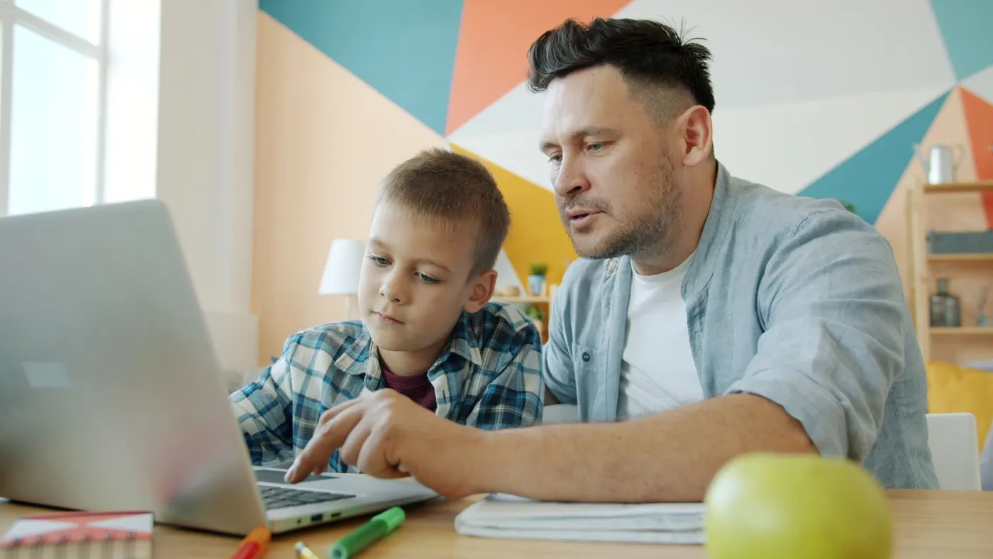 A parent and child looking at homework on a laptop